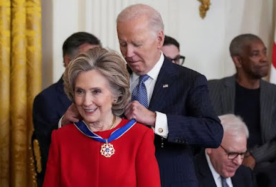 Prank-O-Rama – ‘Joe Biden’ Should Have Just Draped Wreaths Of Garlic Around The Necks Of Mrs. Clinton, Liz Cheney, And Alex Soros (Standing In For Ol’ George), Instead of Medals